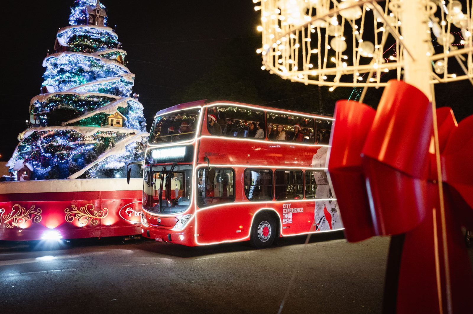 Ônibus com o letreiro Illumination parado sob arcos de luzes coloridas