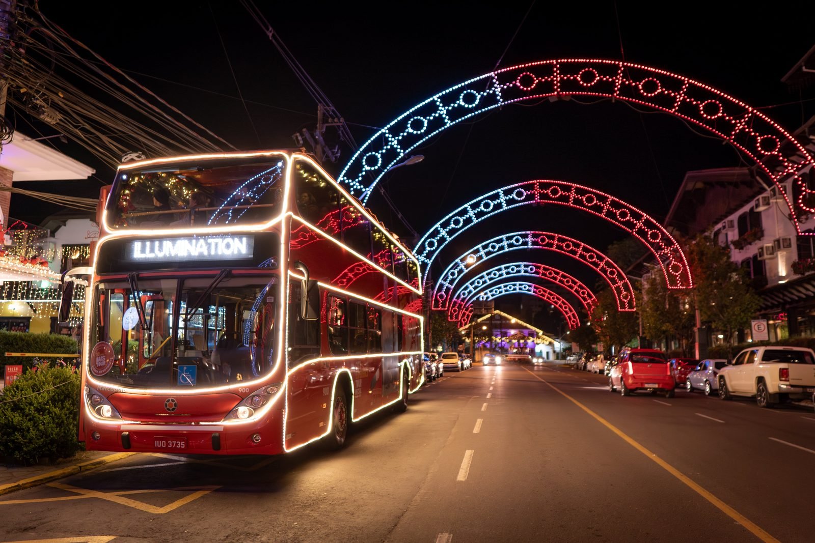Ônibus decorado com árvore de Natal no andar superior em rua iluminada