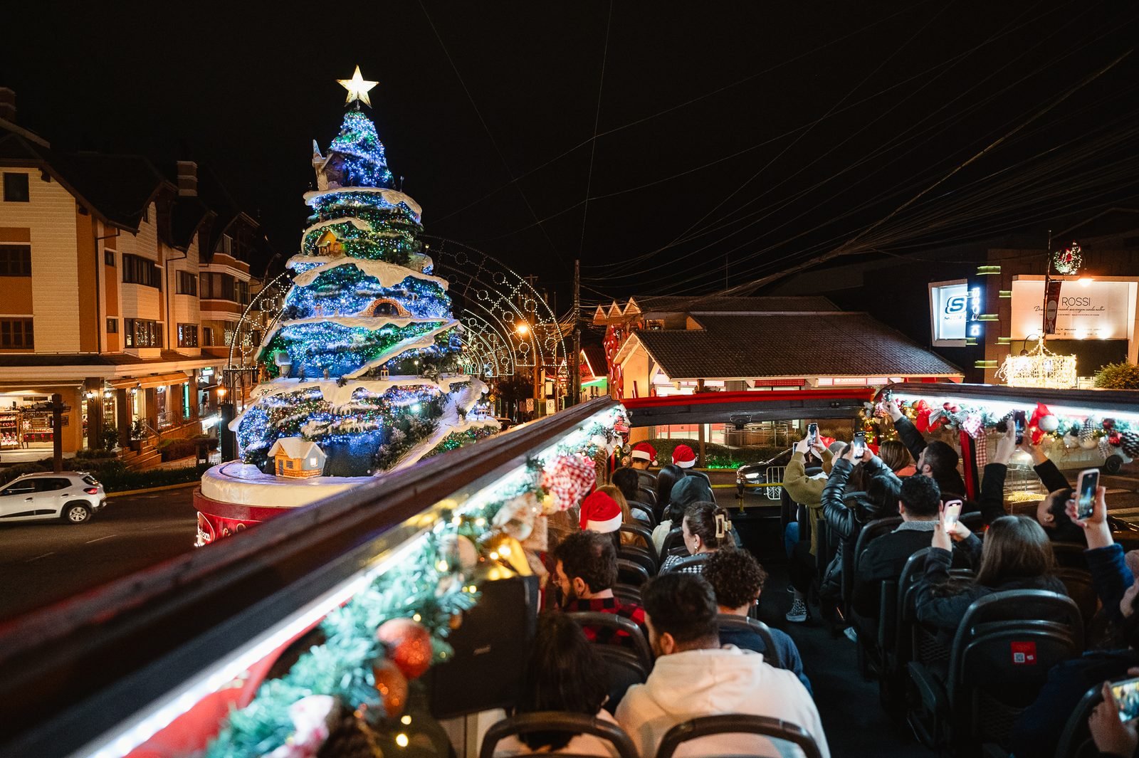 Passageiros fotografando uma grande árvore de Natal decorada a partir do ônibus