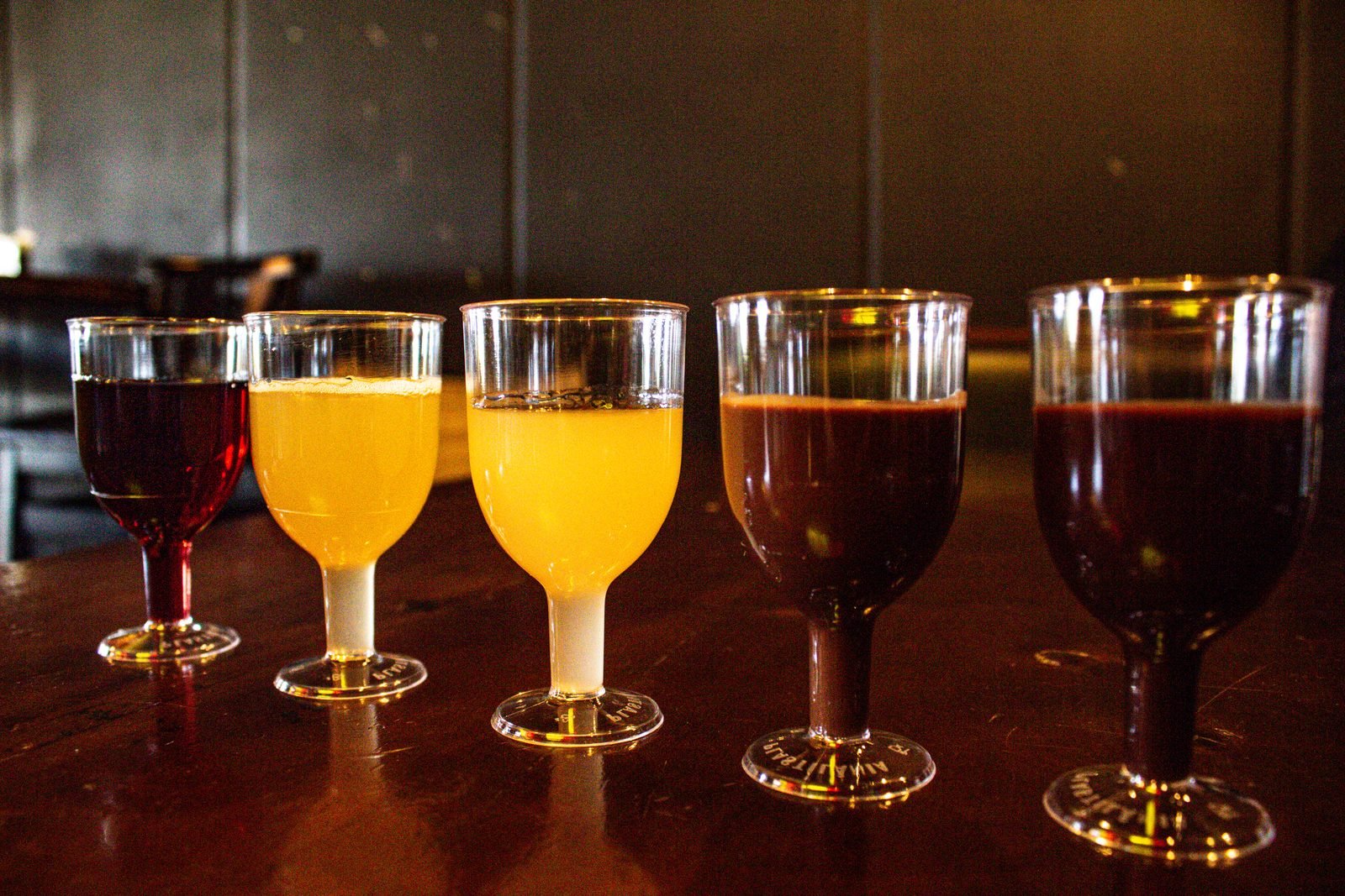 Salão do bar da cervejaria com tecidos coloridos no teto e mesas altas