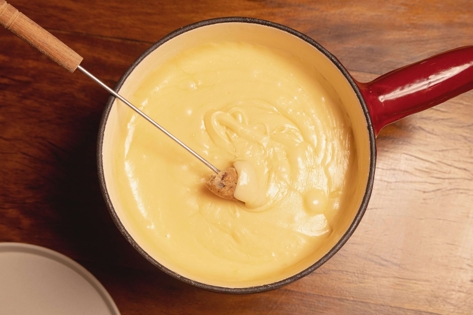 Panela de fondue de queijo vista de cima, com pão espetado no garfo