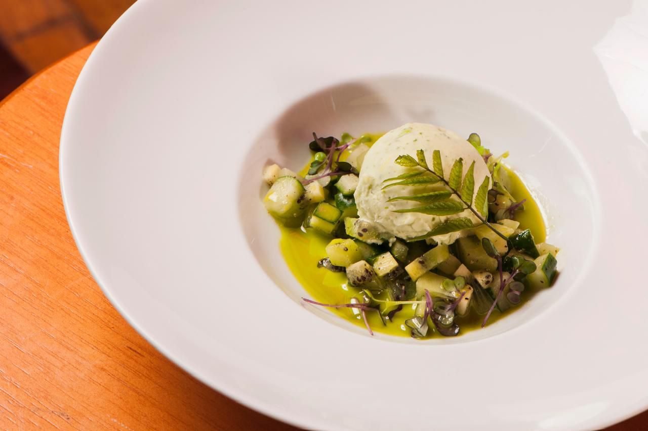 Prato branco com quenelle e legumes em cubos sobre molho verde
