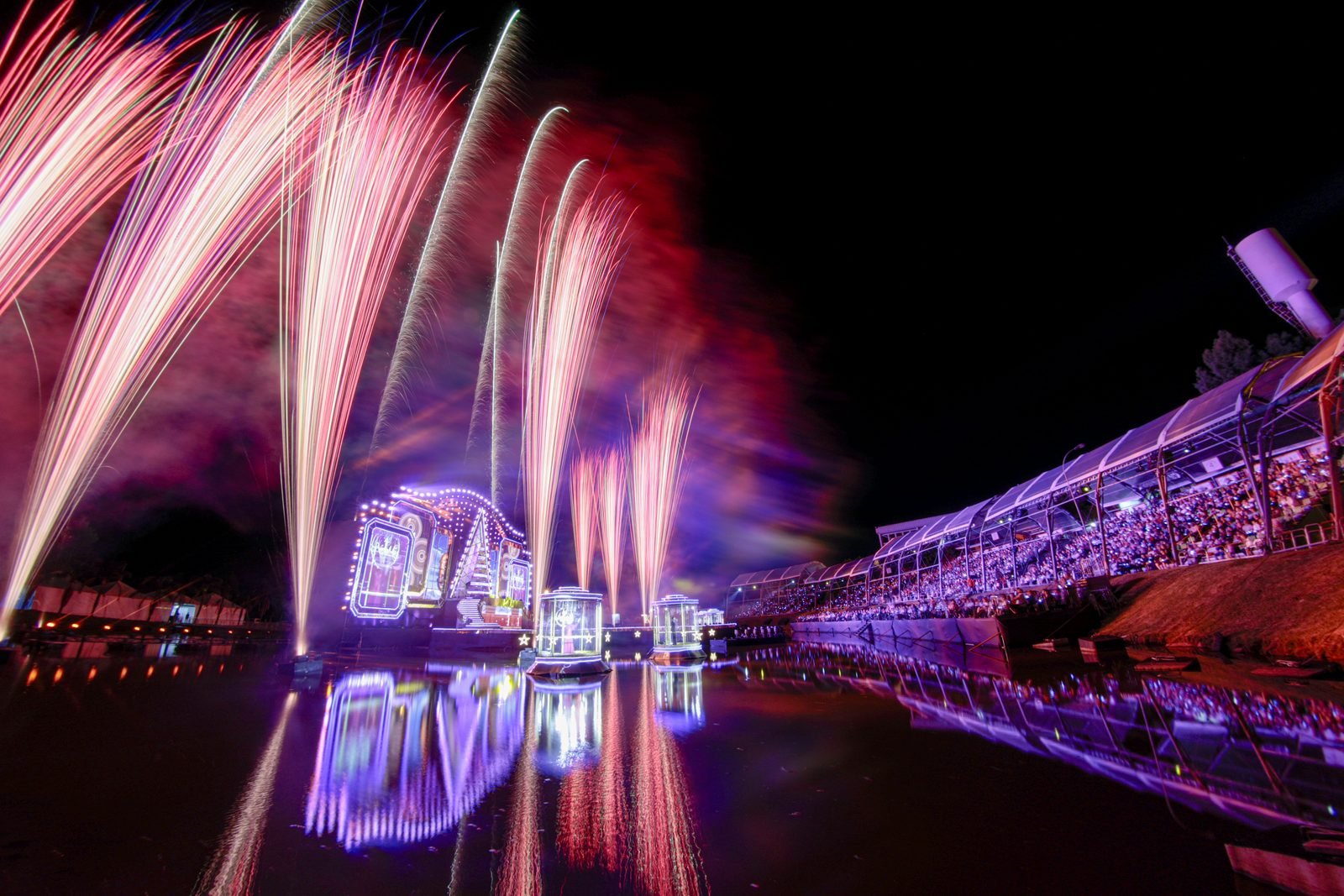 Palco flutuante iluminado refletido na água do lago à noite