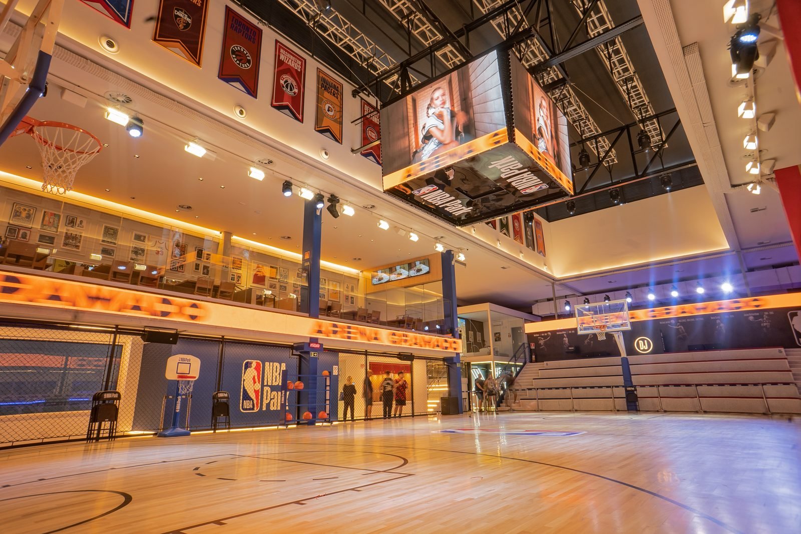 Interior da arena do NBA Park com placar suspenso, arquibancada e bandeiras de times da liga