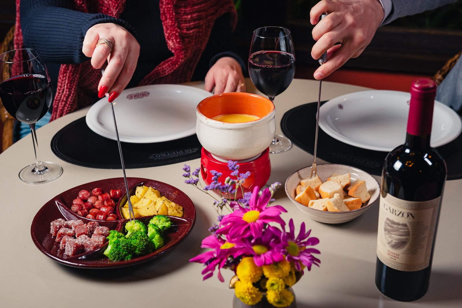 Panela de fondue de queijo servida à mesa com acompanhamentos