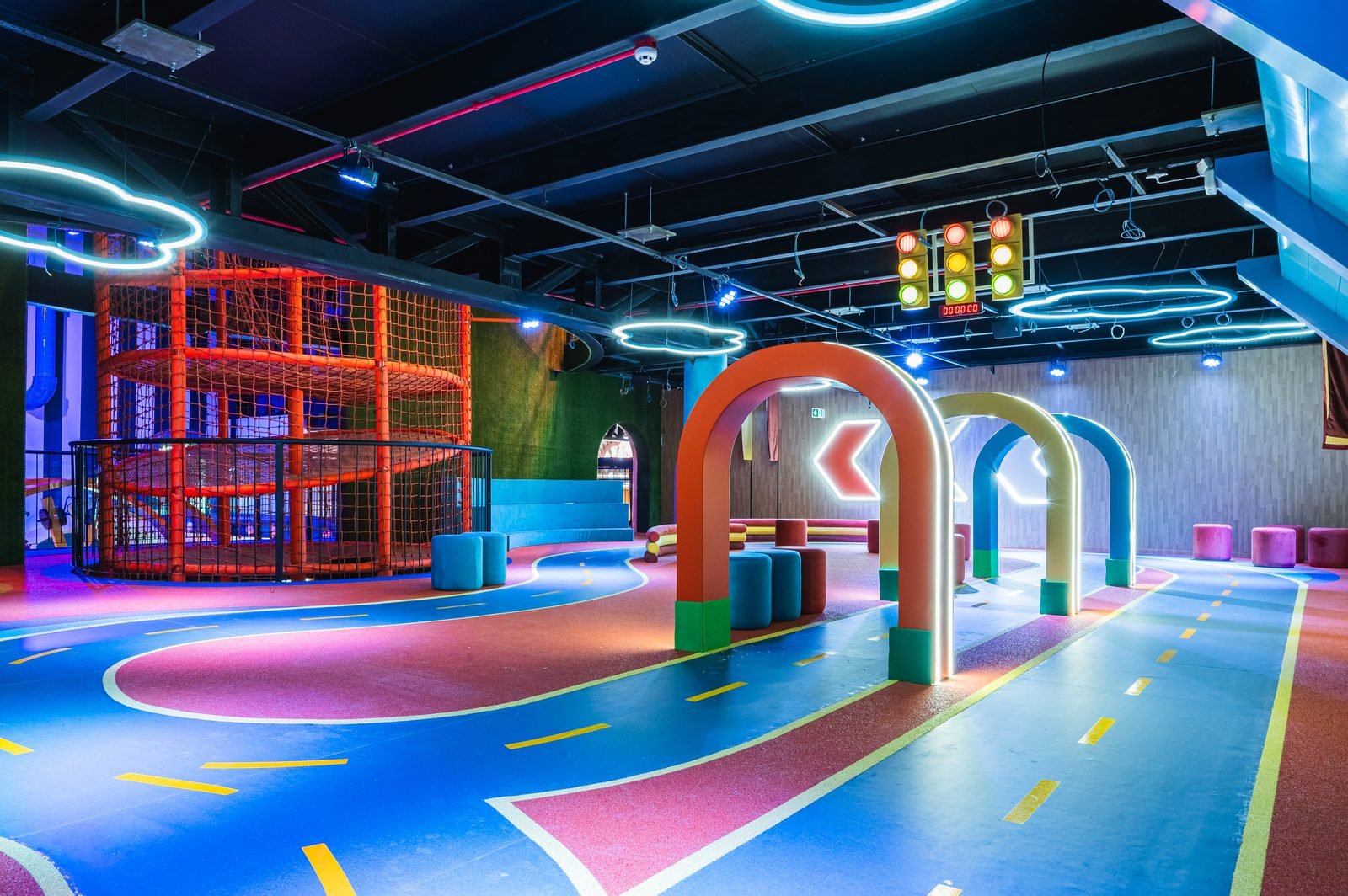 Circuito com piso pintado, arcos iluminados em neon e estrutura de escalada em rede