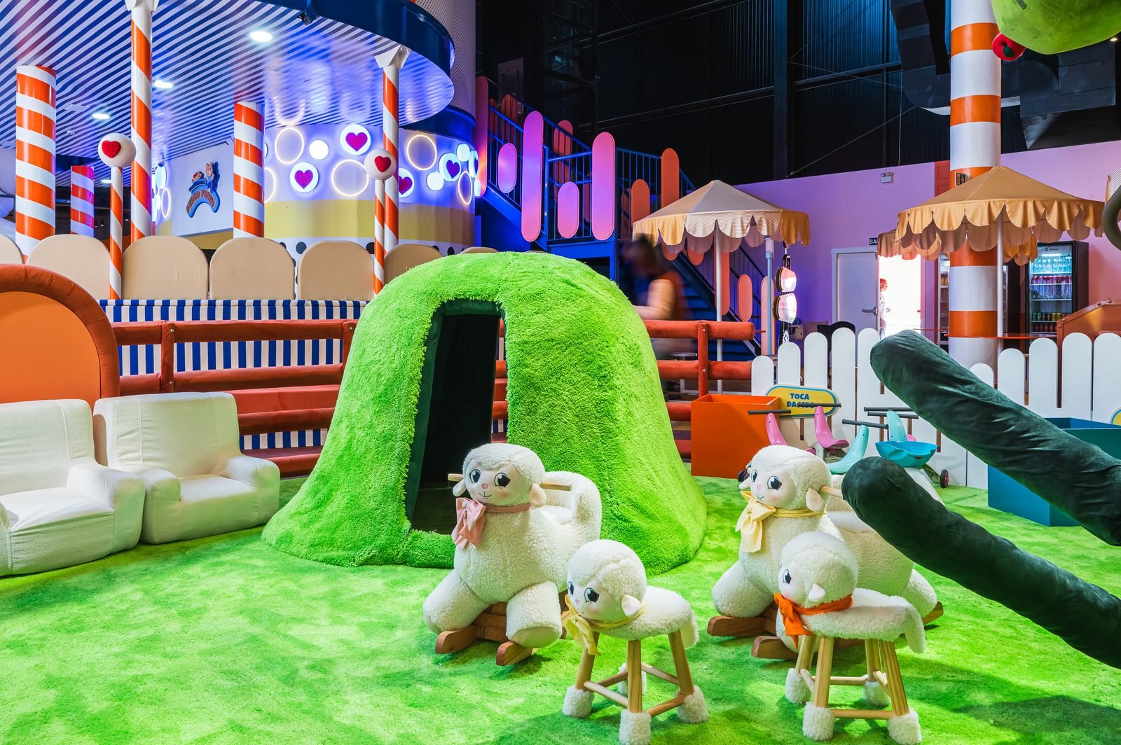 Área com gramado sintético, ovelhas de pelúcia e toca verde para entrar